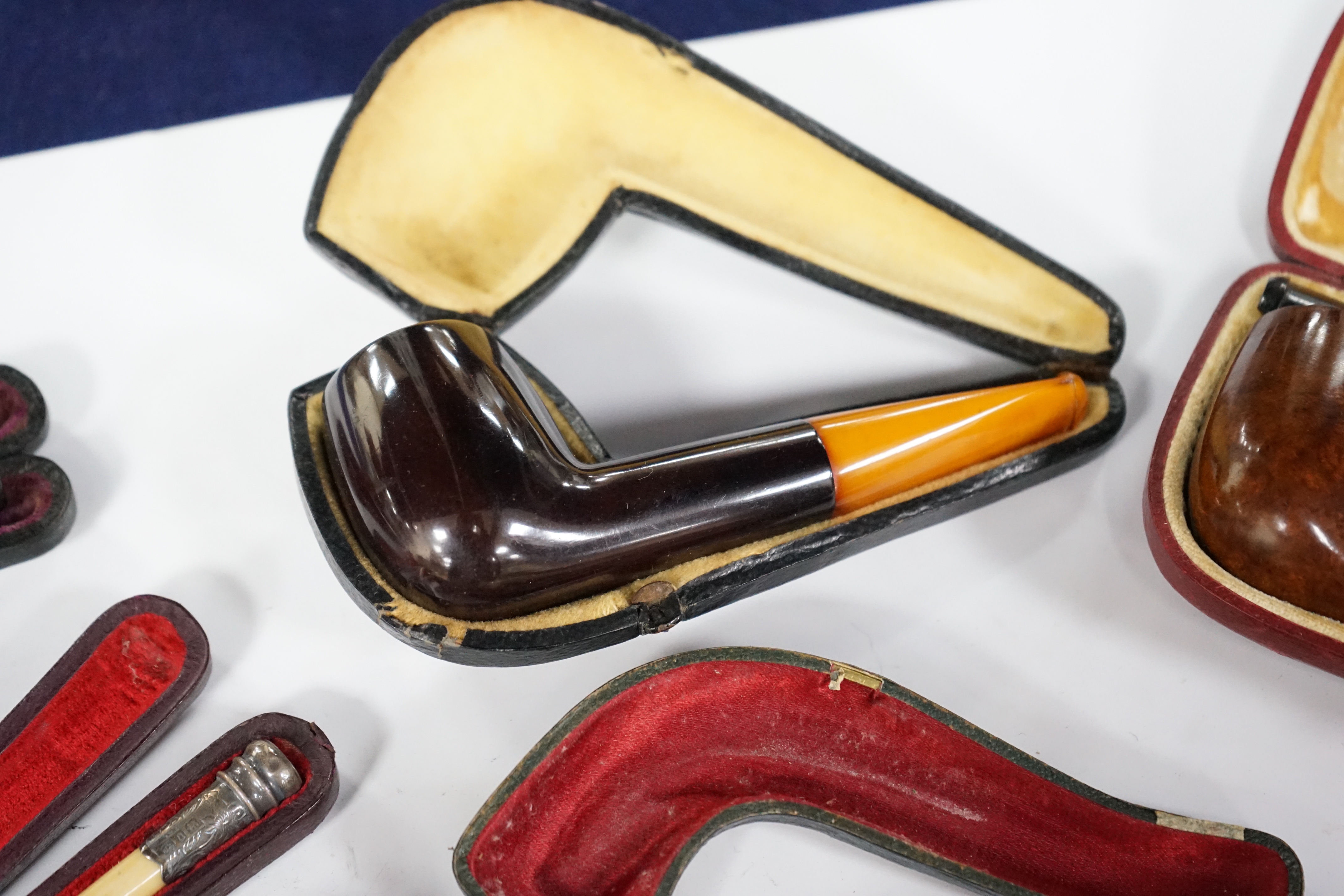 Seven cased pipes in varying sizes, some with amber mouthpieces, largest 19cm long